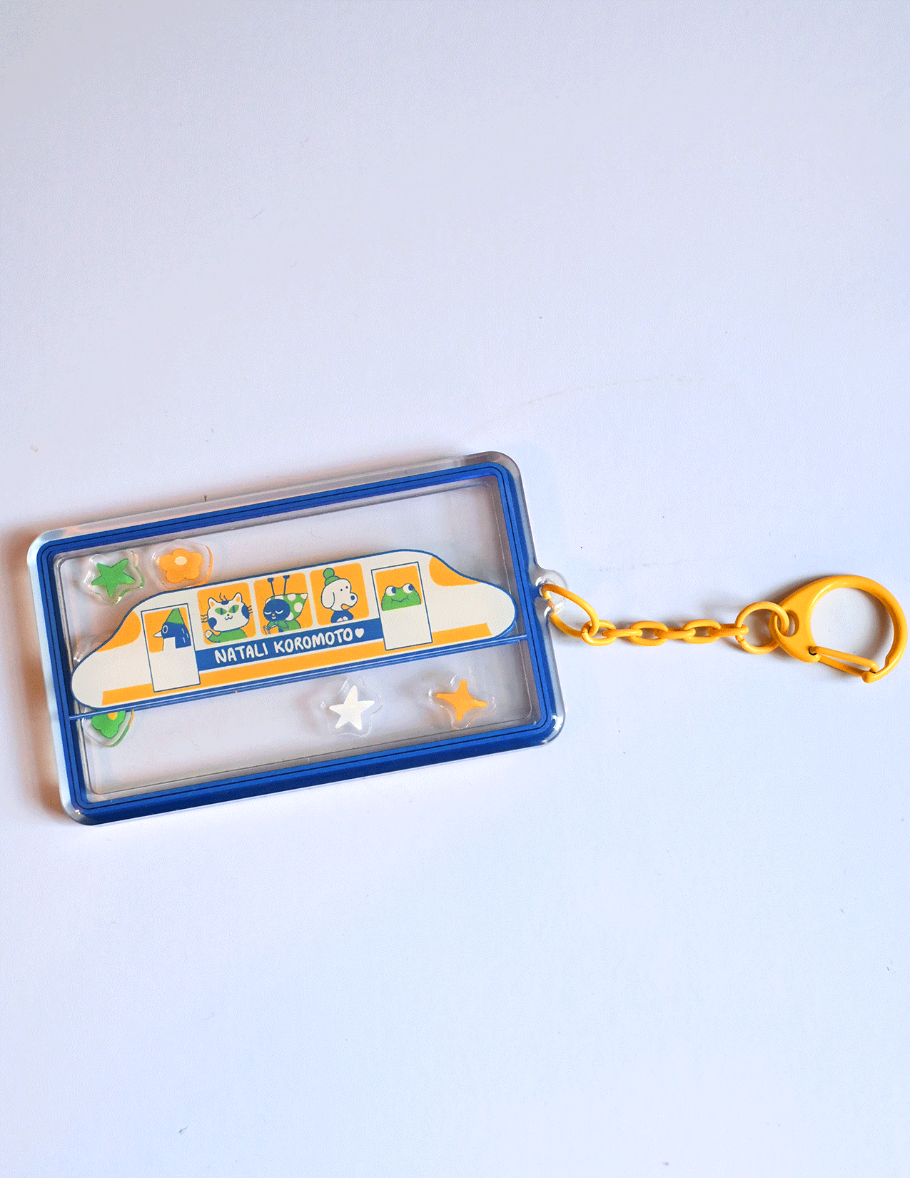 Passengers shaker acrylic keychain by Natali Koromoto featuring animal characters on a Shinkansen train with star and flower charms, double-sided design
