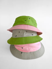 Natali Koromoto x HO HOS HOLE IN THE WALL brand "Ants on Your Hat" printed bucket hat in Avocado Green and True Pink dye colorway combo