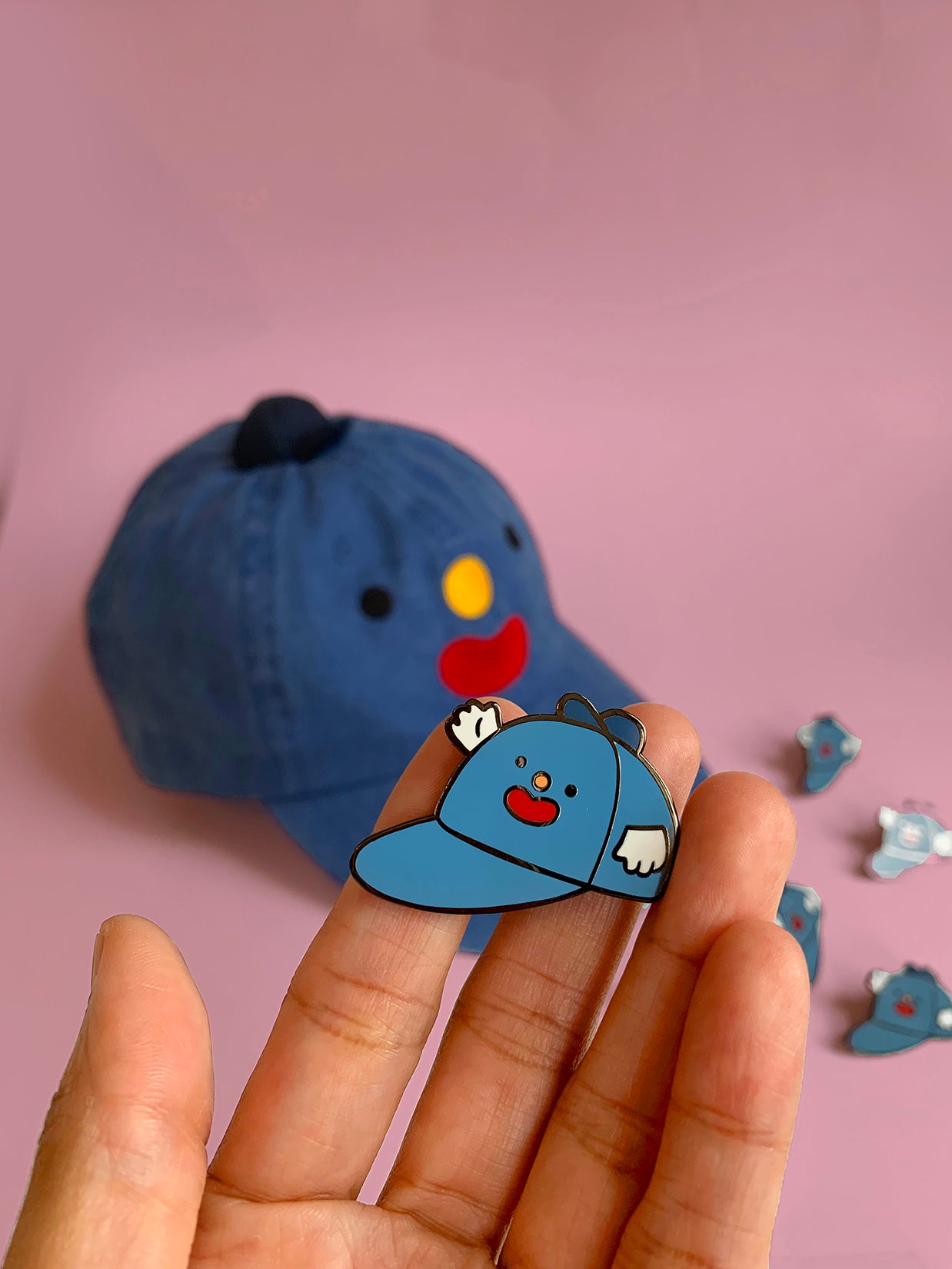 Home to the original hat wearing a hat, "Hat on Hat," designed by artist Natali Koromoto Martinez. This is an enamel pin of the original "Hat on Hat" illustration.