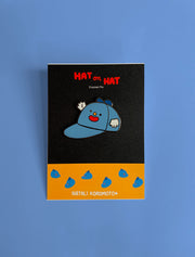 Home to the original hat wearing a hat, "Hat on Hat," designed by artist Natali Koromoto Martinez. This is an enamel pin of the original "Hat on Hat" illustration.
