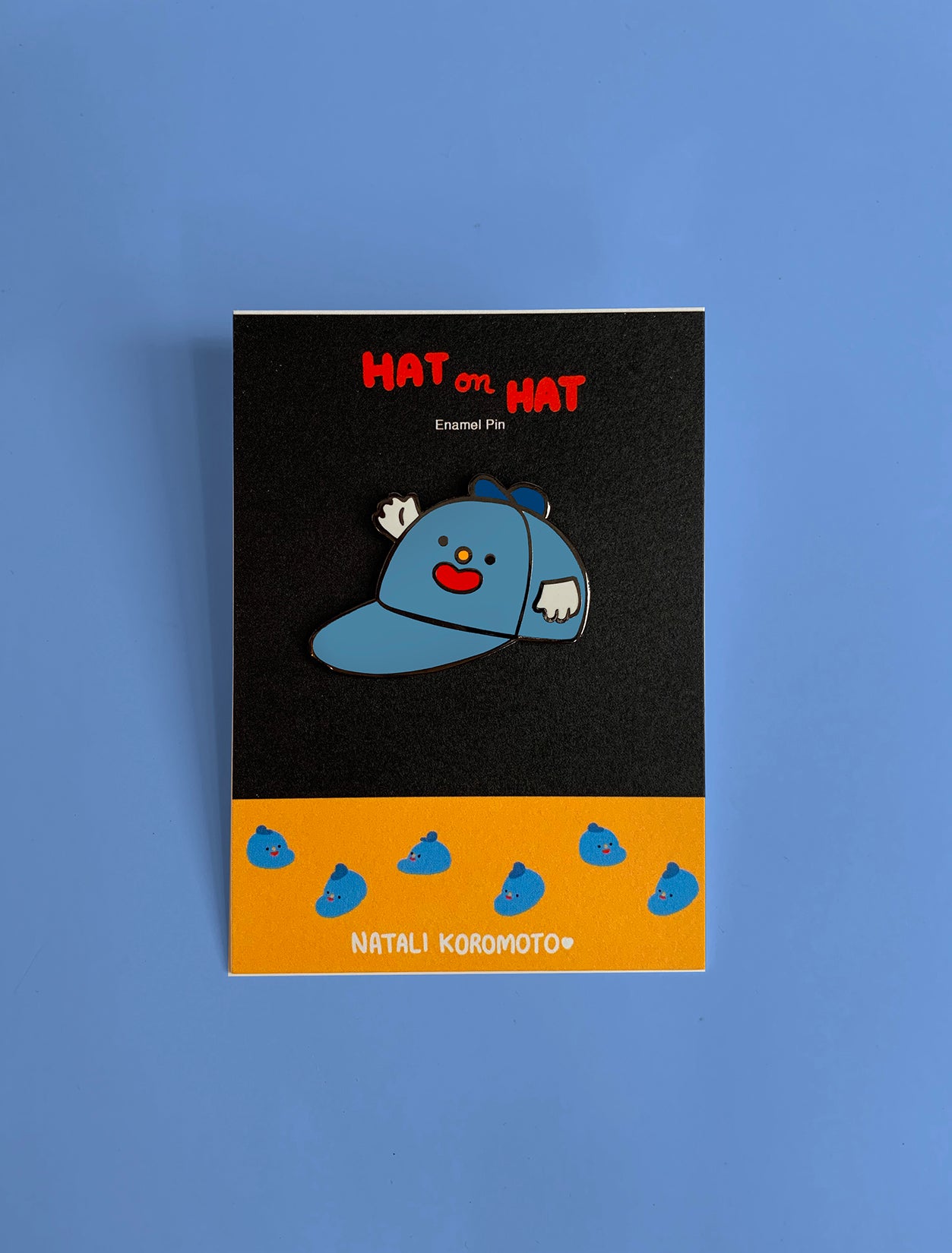Home to the original hat wearing a hat, "Hat on Hat," designed by artist Natali Koromoto Martinez. This is an enamel pin of the original "Hat on Hat" illustration.