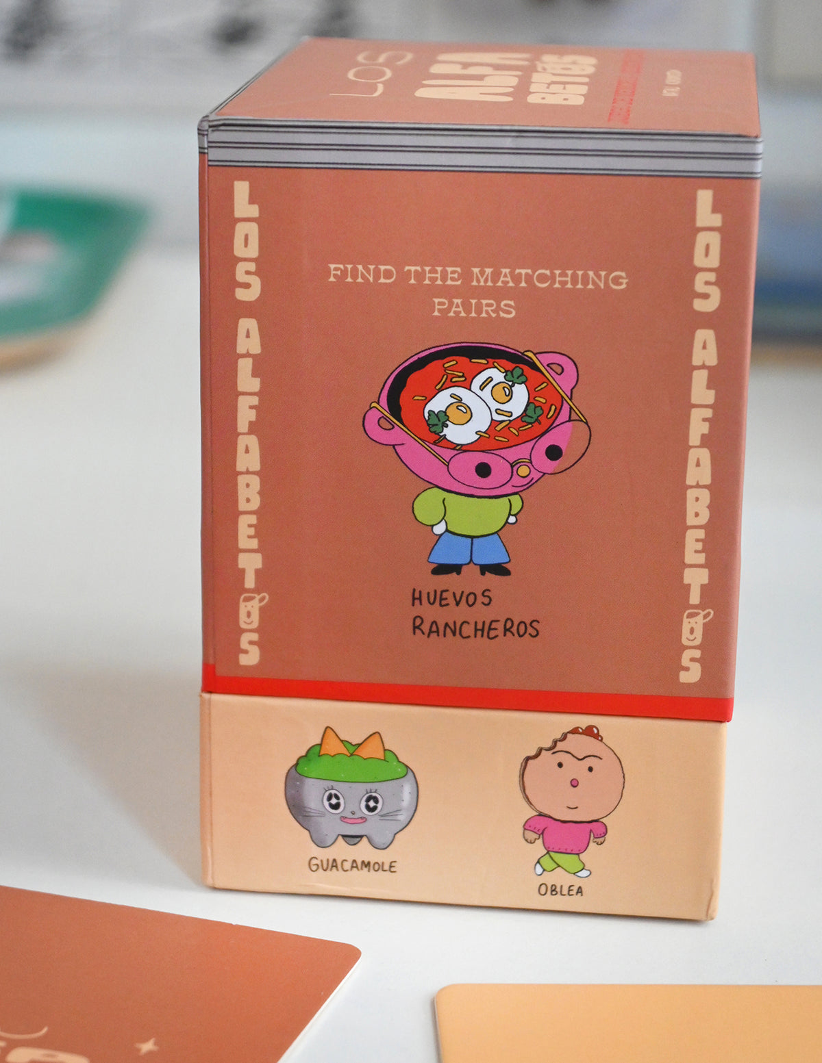 "Los Alfabetos" is a memory card matching game set of 26 pairs of Latin food characters. Designed by illustrator Natalí Koromoto Martínez.