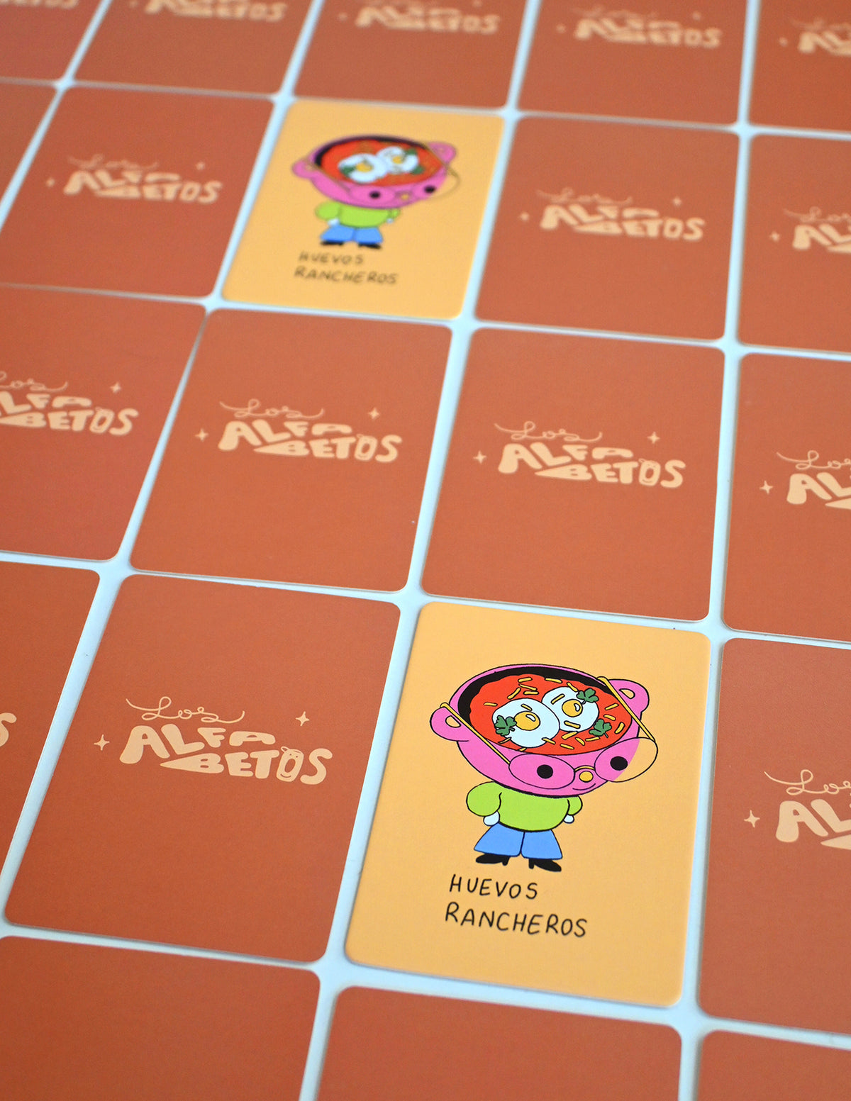 "Los Alfabetos" is a memory card matching game set of 26 pairs of Latin food characters. Designed by illustrator Natalí Koromoto Martínez.