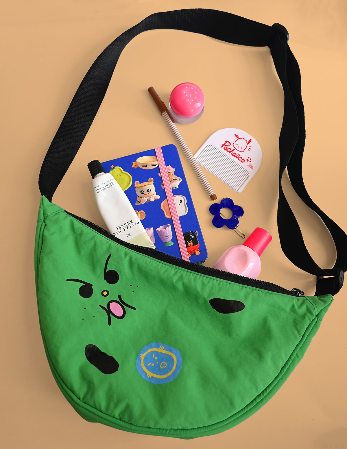 "Bad-nana" Crescent Bag. Natali Koromoto design NYC.
- A colorful cartoon illustration of a green banana-like character with an angry face and the words 'Lil' BAD NANA' on a solid pink background.