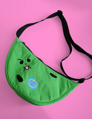 "Bad-nana" Crescent Bag. Natali Koromoto design NYC.
- A colorful cartoon illustration of a green banana-like character with an angry face and the words 'Lil' BAD NANA' on a solid pink background.