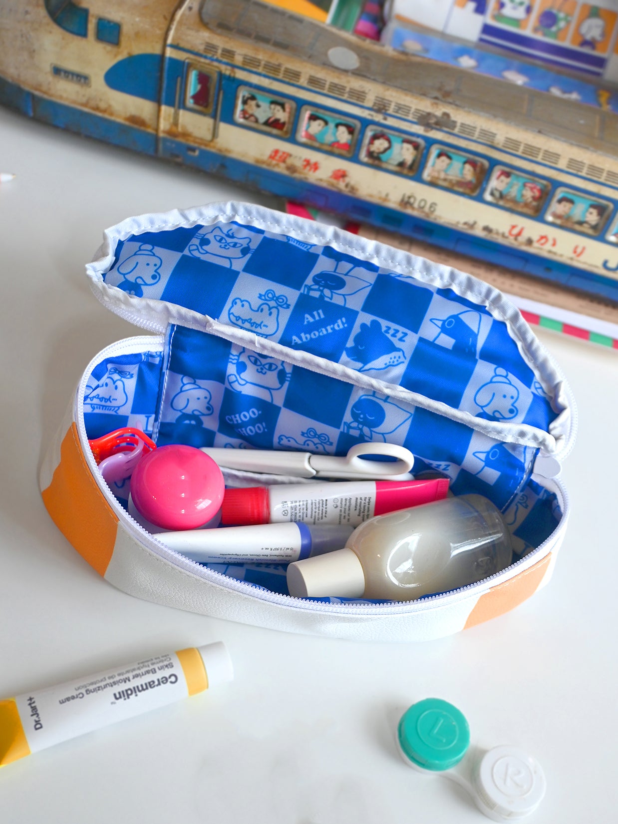 "Passengers" pencil pouch by Natali Koromoto showing inside view with animal characters printed on the lining in a checkerboard pattern. Shows makeup and tools like scissors and hairclips as contents.