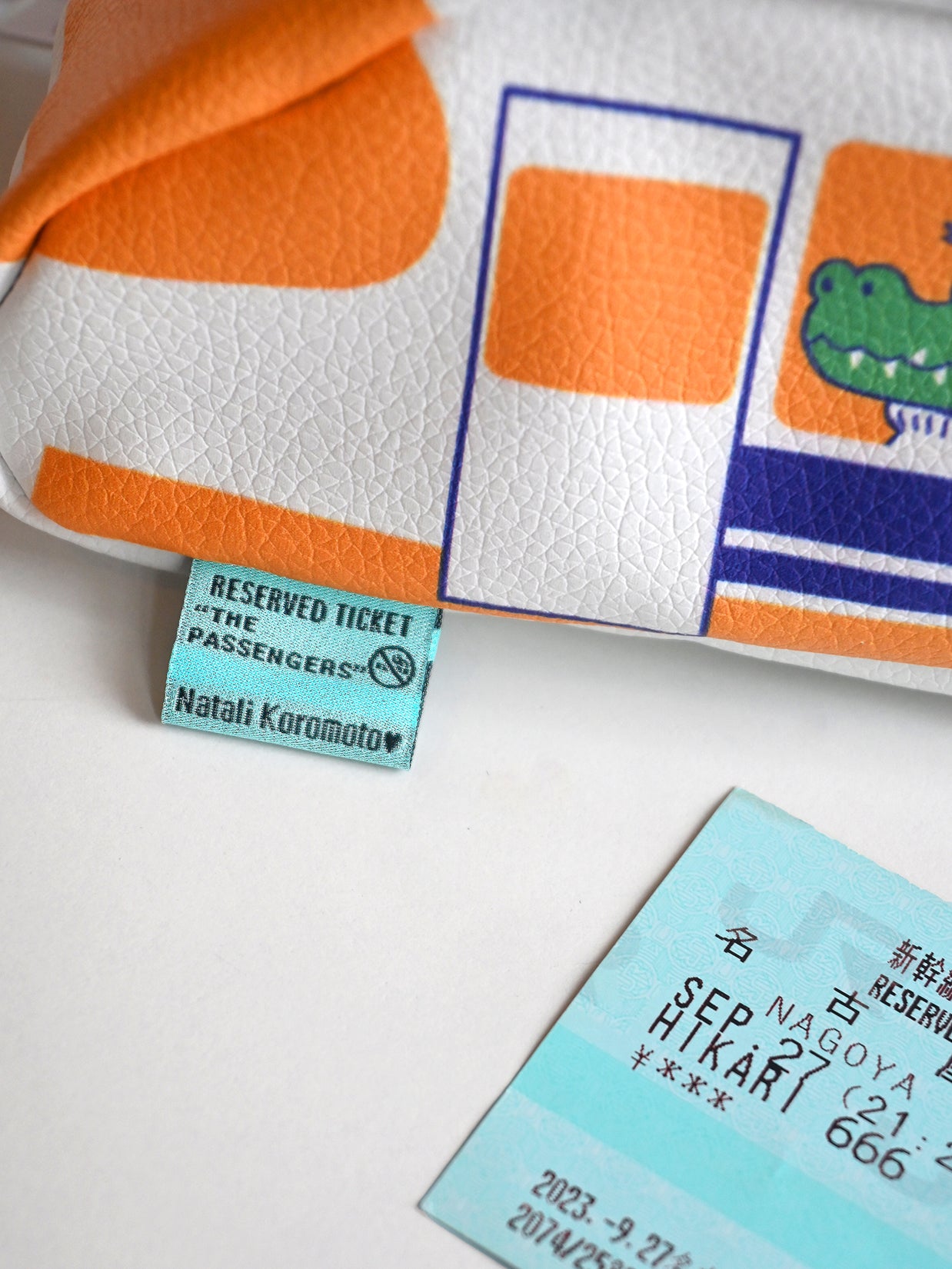 "Passengers" pencil pouch by Natali Koromoto showing closeup of the brand tag, which is a "Reserved Ticket" for "The Passengers".